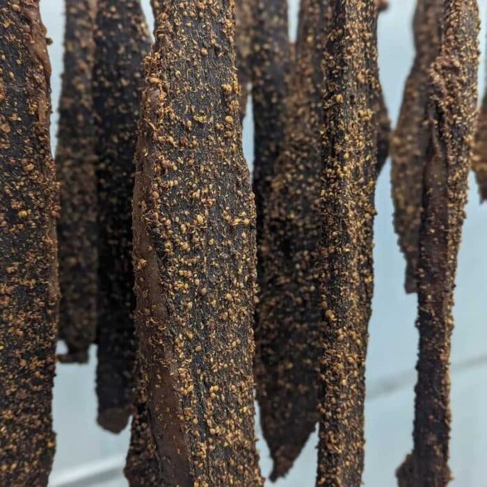 A close up of biltong slabs hanging from a drying rack