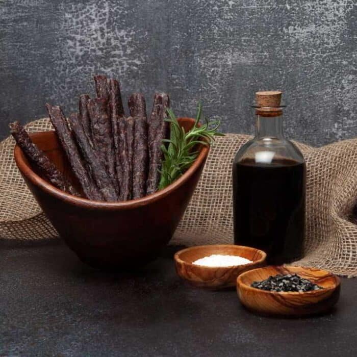 A bowl of meat sticks or droëwors and a bottle of vinegar and spices