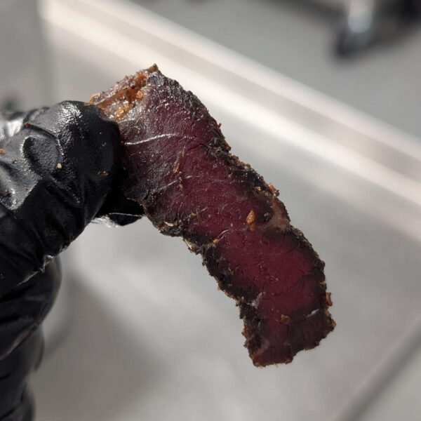 A hand holding High Protein Snacks, such as biltong slices