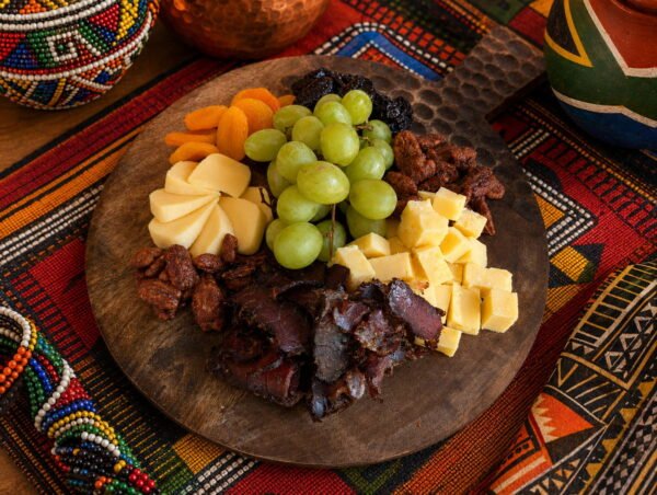Traditional South African charcuterie board with biltong, cheese, grapes, and dried fruit.